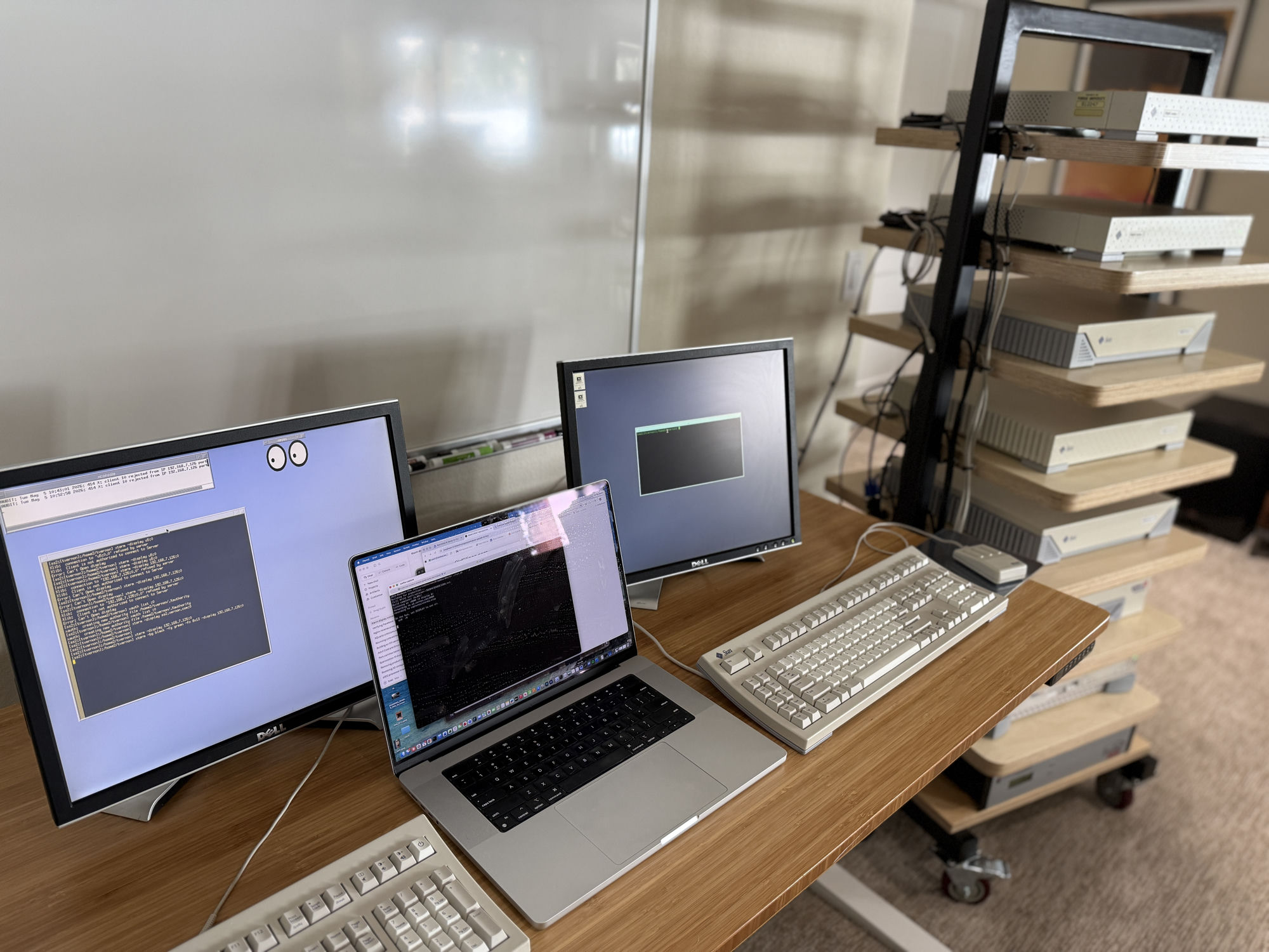 Capture setup at the workbench: a MacBook Pro running the framer and proxy, two Dell monitors showing captured wire log and a live xeyes window, and a rack of Sun pizza box workstations on the right.